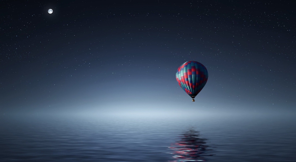 Picture of a hot air balloon alone above the ocean at night, tying into the article about California being an energy island.
